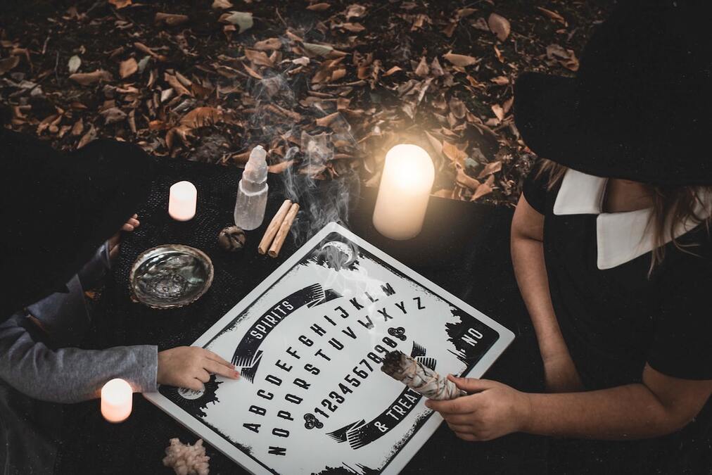 Hipnose e espiritismo - Tabuleiro Ouija sendo jogado por duas pessoas.